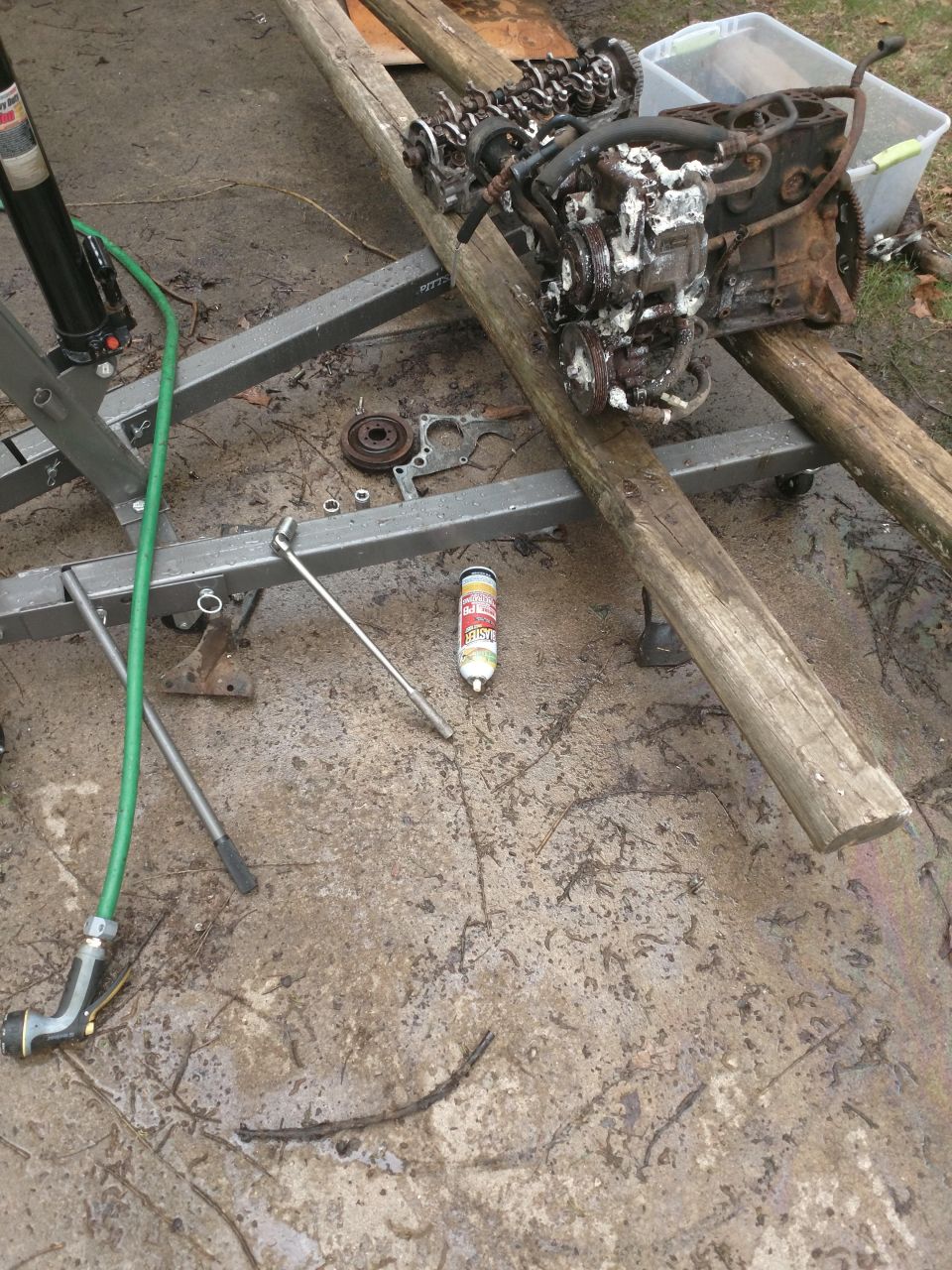 Engine block on hoist with tools on wet ground