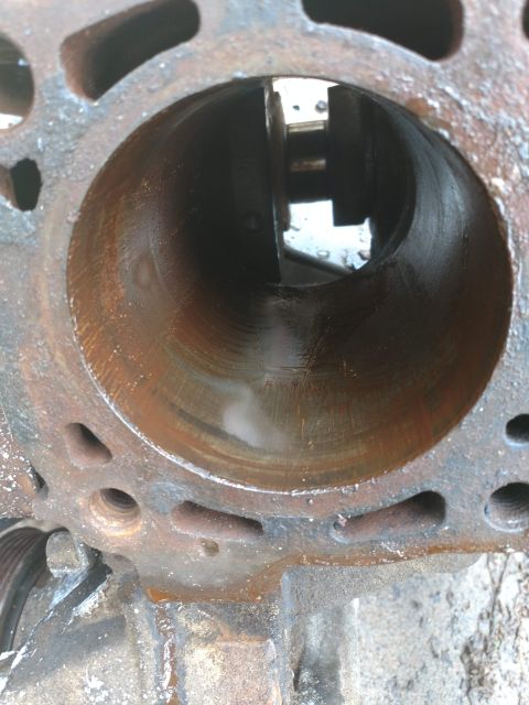 1989 Ford Probe - This is a close-up view of the inside of a rusty engine cylinder bore. The cylinder walls show visible scoring and wear marks.