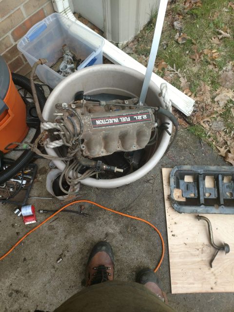 1989 Ford Probe - A disassembled engine intake manifold labeled "2.2L FUEL INJECTION" is sitting in a large tub. Other engine parts and tools are scattered o…