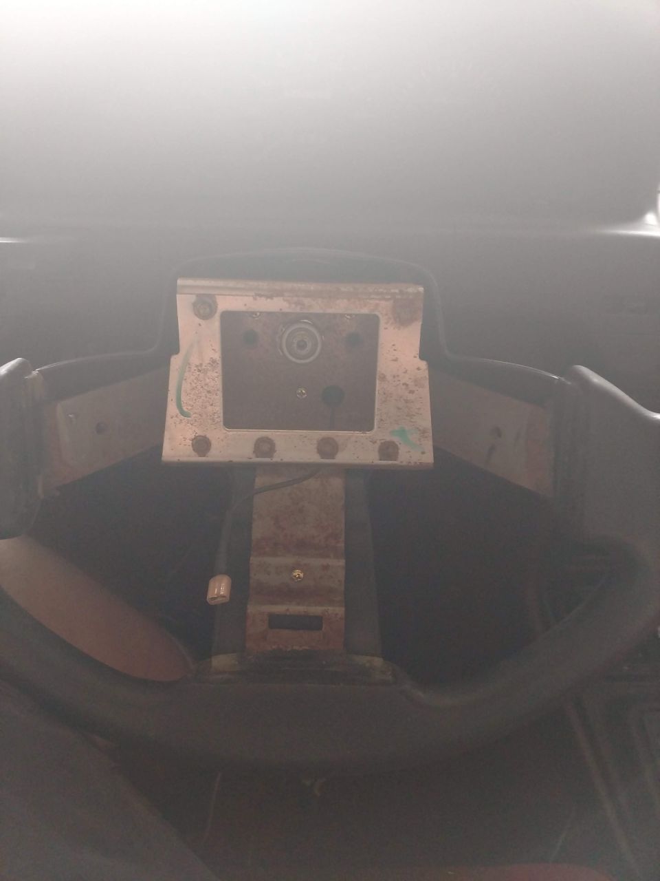 Vehicle steering column with bracket and wiring visible.