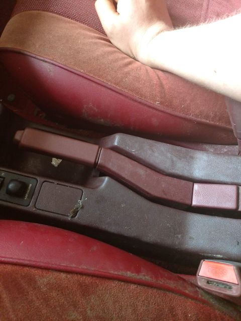 1989 Ford Probe - The interior of a car shows a close-up of the center console area, including the handbrake lever and part of a seat.