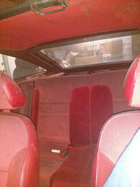 1989 Ford Probe - The interior of a vintage car with red upholstery is shown. Visible in the background through the rear window is a sign that reads "THE BEA…