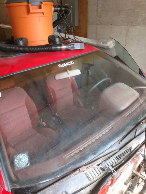 1989 Ford Probe - A close-up, slightly dusty interior view of a red car, possibly a 1989 Ford Probe, showing the dashboard, windshield, and front seats. A sh…