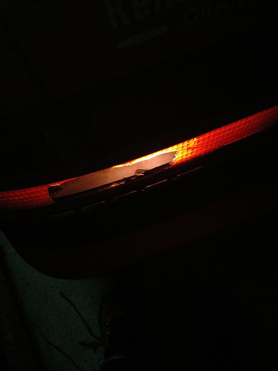 Close-up of an illuminated car taillight with a textured red lens.