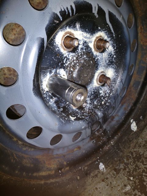 1989 Ford Probe - A close-up view of a rusty wheel hub with a socket wrench attached to one of the lug nuts. White residue is visible around the lug nuts and…