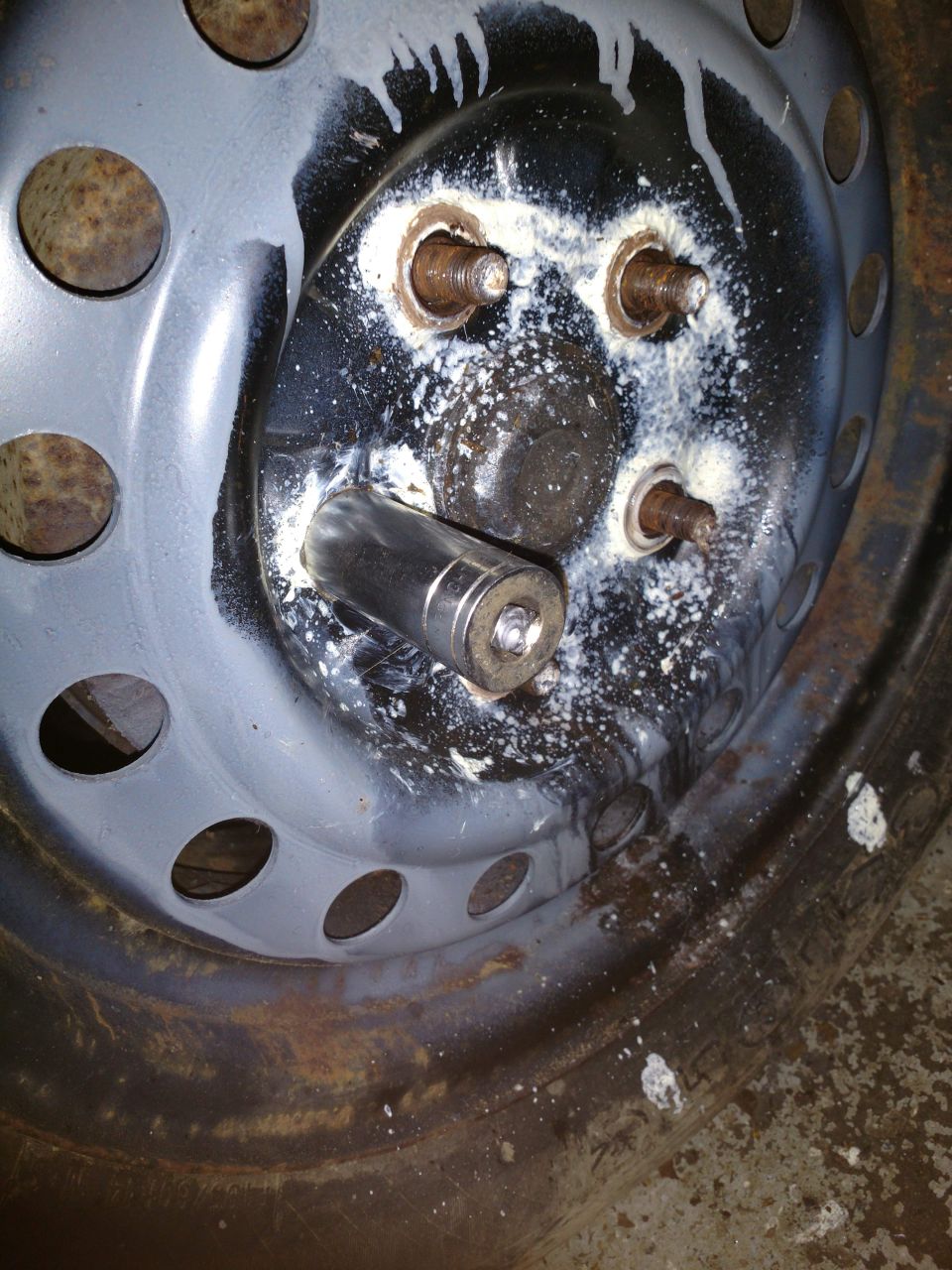 Close-up of a rusty wheel hub with a socket wrench on a lug nut.