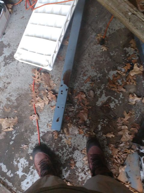 1989 Ford Probe - A person's legs and feet wearing work boots are visible standing on a concrete floor littered with fallen leaves. A white plastic object an…