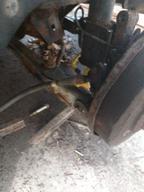 1989 Ford Probe - A close-up view of the rusty suspension and brake components of a vehicle, including a brake line and part of the wheel hub.