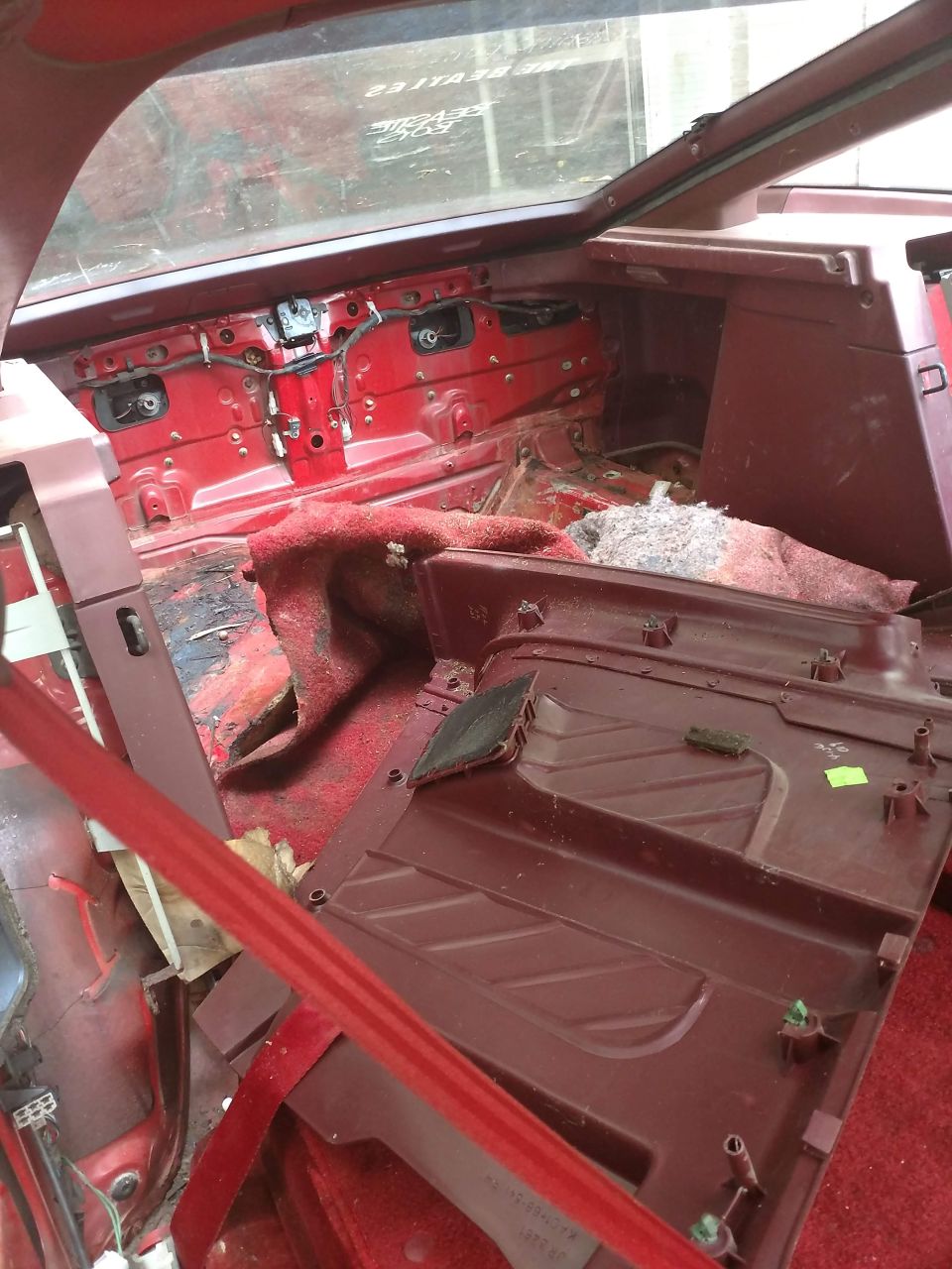 Disassembled vehicle interior with red metal body and maroon plastic trim.