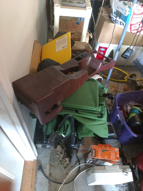 1989 Ford Probe - This image shows a cluttered storage area with various items including a brown plastic car part, green fabric, boxes, and a purple bin. The…