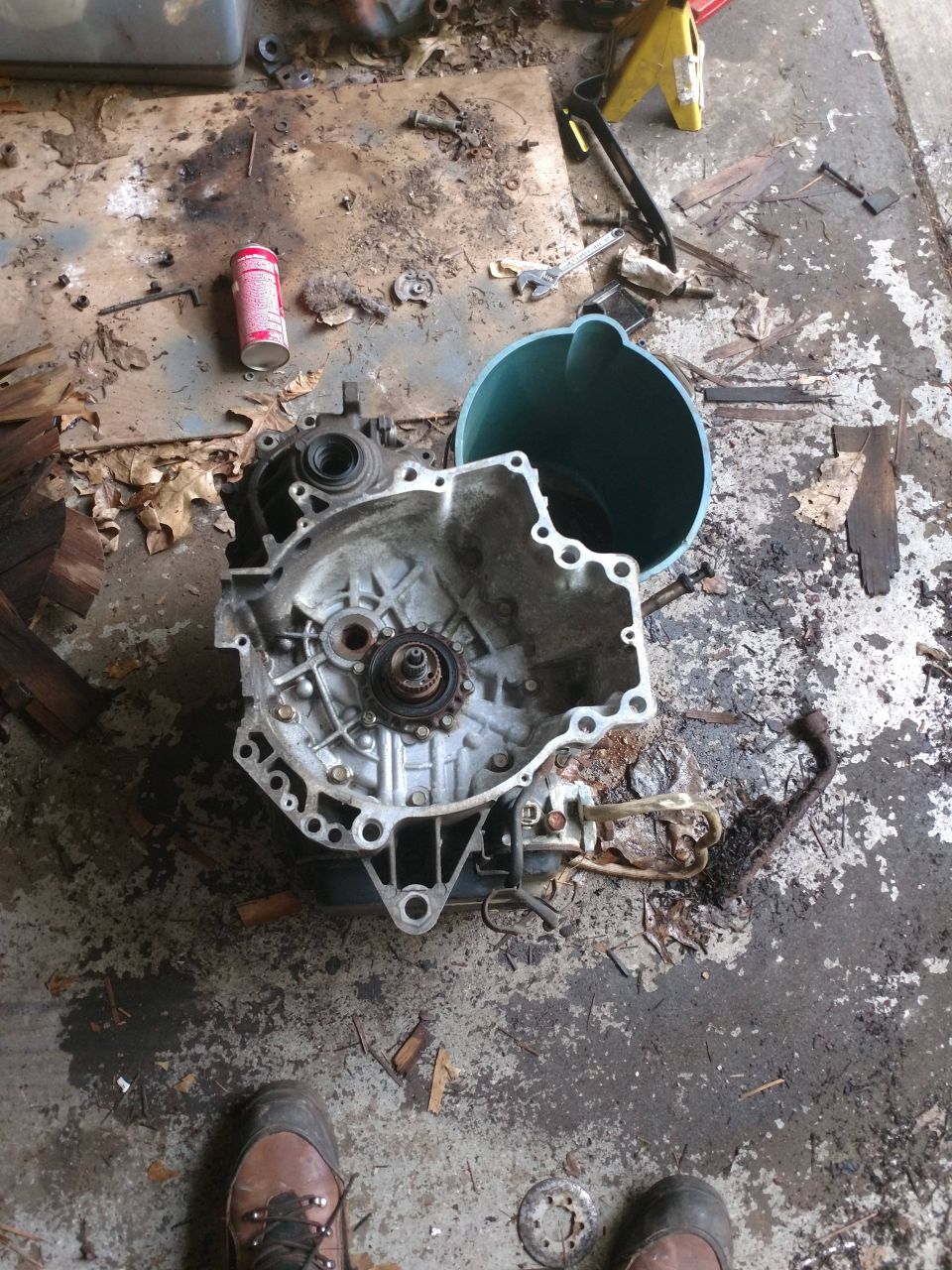 Disassembled car transmission on a dirty garage floor.