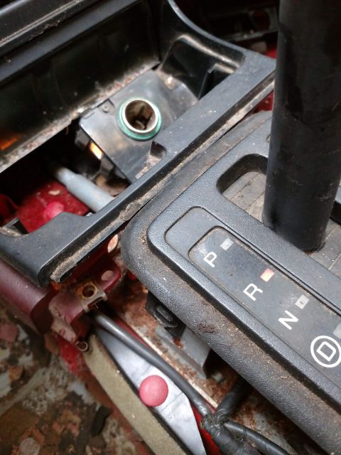 1989 Ford Probe - Close-up interior view of a car's center console, showing a gear shifter with a P-R-N-D indicator and a cigarette lighter socket. The area…