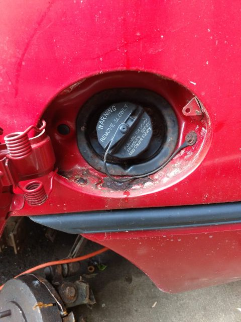 1989 Ford Probe - Close-up of a red car's fuel filler door, showing part of the body and trim.
