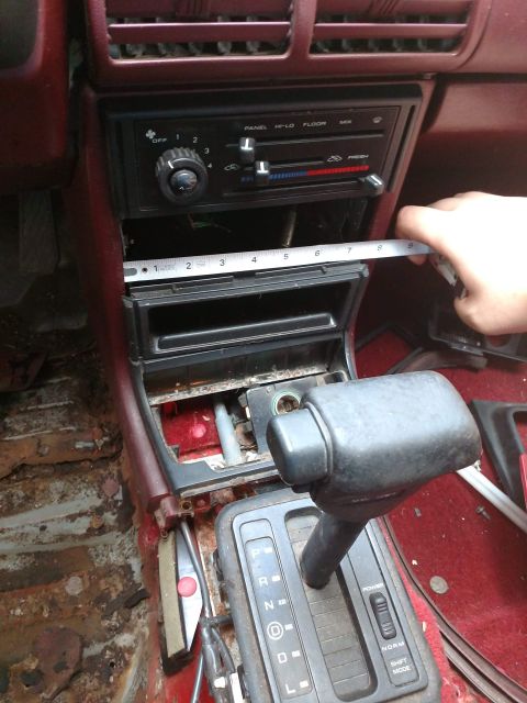 1989 Ford Probe - Measuring the center console area of a car interior, with visible rust on the floor.