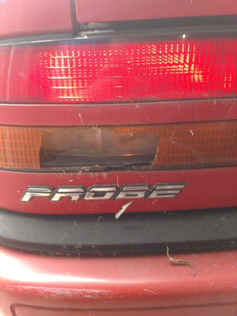 1989 Ford Probe - Damaged rear taillight assembly on a red car with 'PROBE' badging.