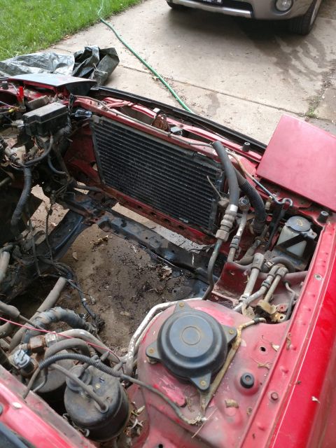 1989 Ford Probe - Engine bay of a red car, showing the radiator and associated components during a repair process.
