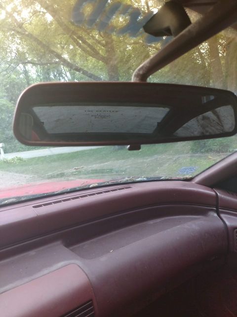 1989 Ford Probe - The rearview mirror and dashboard of a vehicle are shown, with some text visible in the mirror.