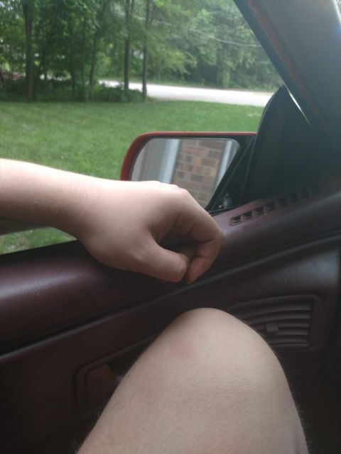 1989 Ford Probe - View from inside a vehicle showing the door panel and armrest, with a hand resting on the door.