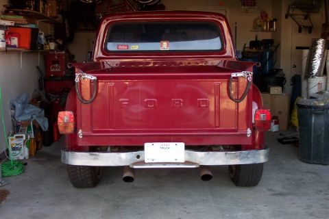 1968 Ford F-100 - The back of a red Ford pickup truck is shown parked inside a garage with various items stored around it.