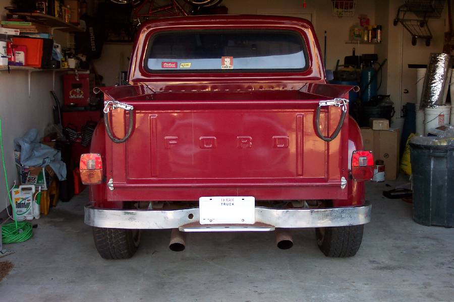 Rear view of red classic Ford stepside pickup with stamped FORD tailgate and dual exhaust tips