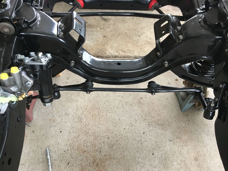 Black painted vehicle frame with suspension parts, including tie rods and steering components