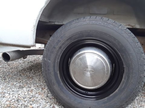 1999 Ford E250 - A close-up view of a Ford van's wheel, showing the tire, hubcap, and exhaust pipe.