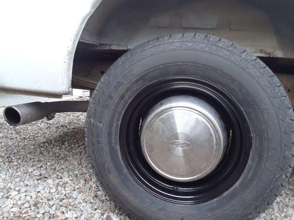 Close-up of a Ford van's rear wheel, hubcap, and exhaust pipe