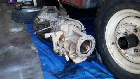 1985 Ford Bronco - A disassembled transmission sits on a blue tarp in a garage setting.