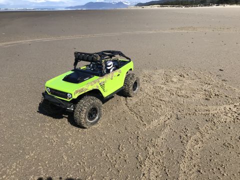 1989 Ford Bronco - A remote-controlled vehicle sits on a beach, its tires leaving tracks in the sand.