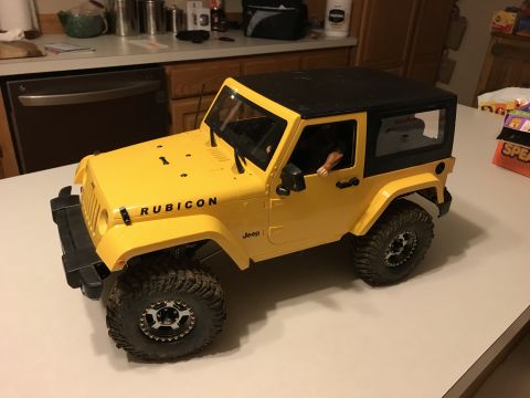 1989 Ford Bronco - A yellow Jeep Wrangler Rubicon model with a black hardtop sits on a countertop.