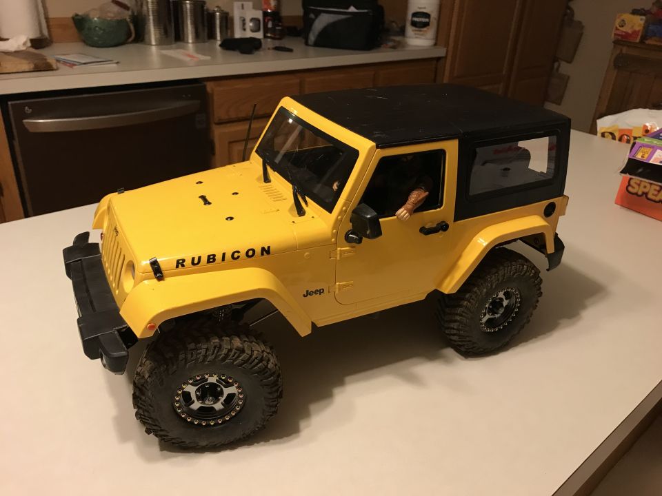 Yellow Jeep Wrangler Rubicon with black top and off-road tires
