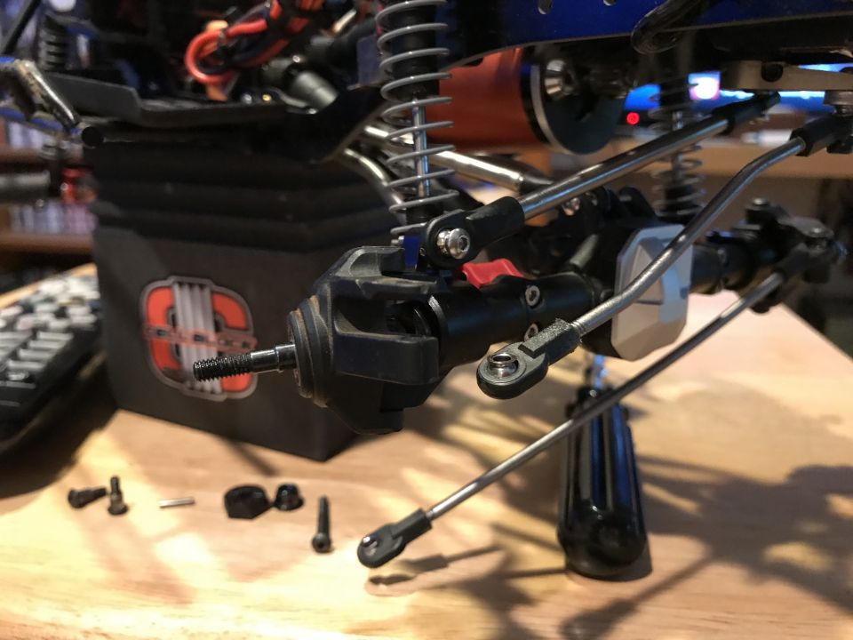 Close-up of RC car suspension components and screws on a wooden surface