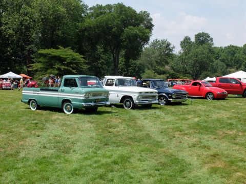 1971 Ford Ranchero - A line of pickup trucks and cars are displayed on a grassy field under a clear sky.
