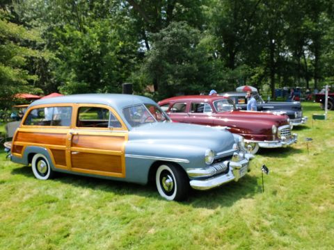 1971 Ford Ranchero - A classic wood-paneled station wagon is displayed alongside other vintage vehicles on a sunny day.