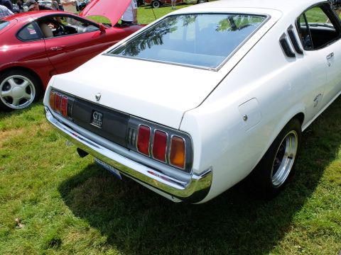 1971 Ford Ranchero - The rear of a white 1970s Toyota Celica GT coupe is shown, with a red car visible in the background.