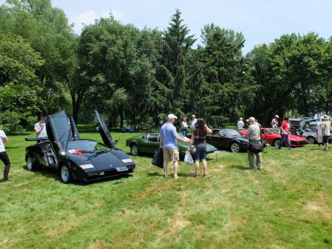 1971 Ford Ranchero - Outdoor car show features a black sports car with doors open, surrounded by spectators and other vehicles.