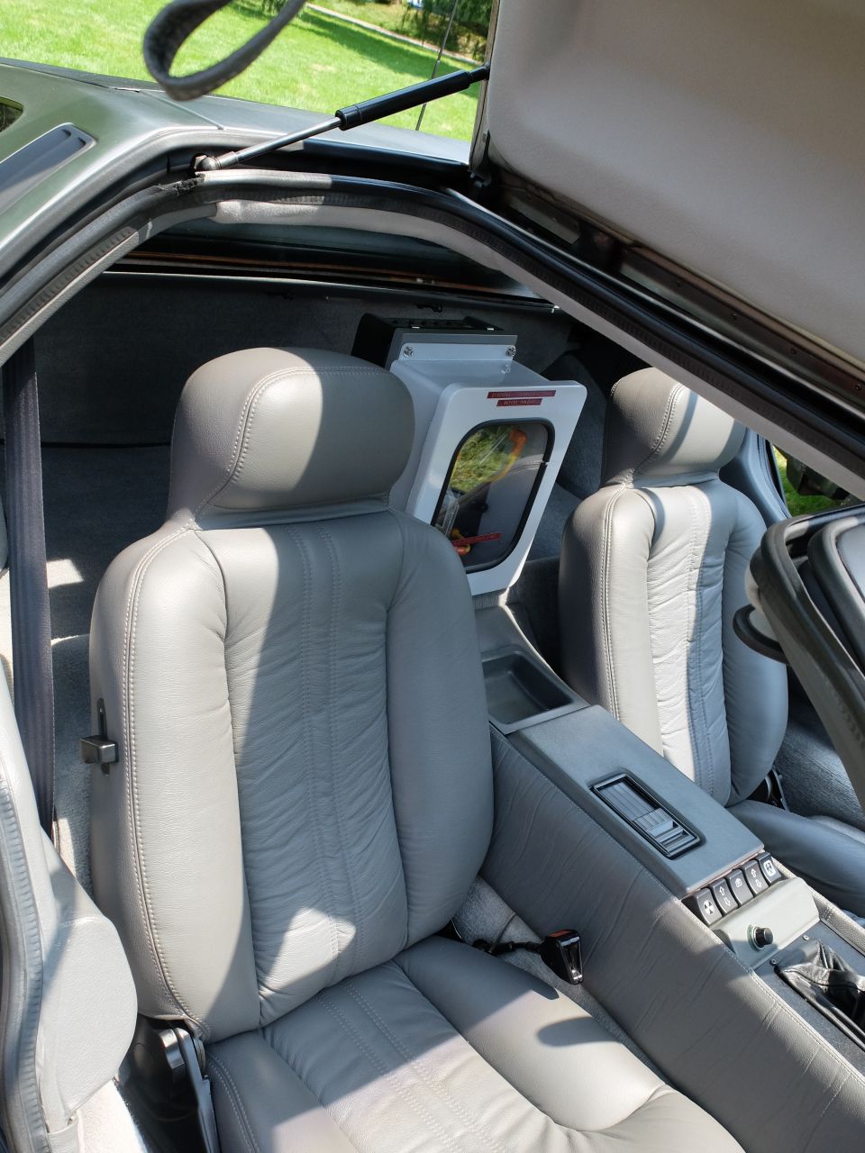 Gray leather car interior with two seats and a central console, showing a white box with a window