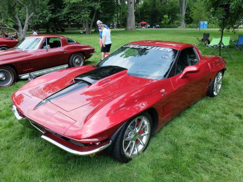 1971 Ford Ranchero - A red 1965 Chevrolet Corvette Sting Ray is parked on grass, with another classic Corvette in the background.