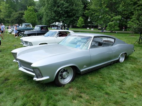 1971 Ford Ranchero - A silver coupe with a unique front end and custom wheels sits on a grassy field with other vehicles.