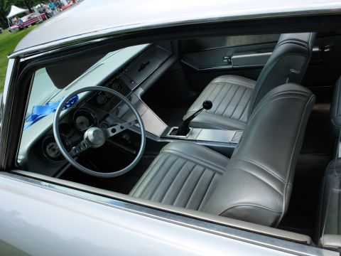 1971 Ford Ranchero - The interior of a classic vehicle is shown, silver upholstery, a three-spoke steering wheel, and a prominent floor shifter.