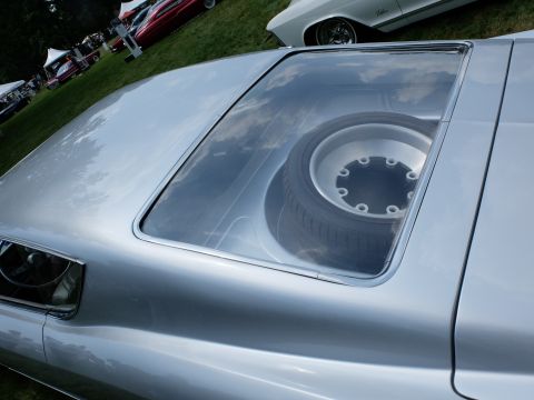 1971 Ford Ranchero - Spare tire visible through the rear window of a silver car at an outdoor event.