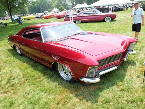 1971 Ford Ranchero - A custom red coupe with a distinctive grille and chrome wheels sits on display at an outdoor event.