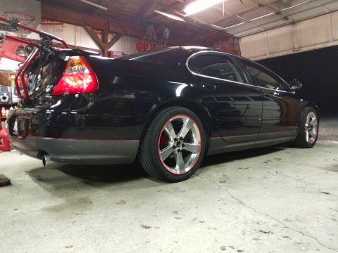 2002 Chrysler 300M - Rear three-quarter view of a black 2002 Chrysler 300M sedan with custom red accents on the wheels and body.