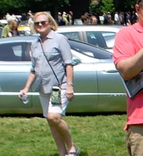 1971 Ford Ranchero - Woman walks past a silver car at an outdoor event with other people in the background.