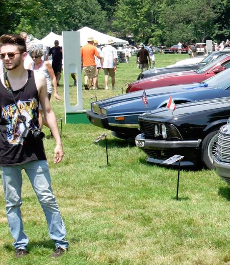 1971 Ford Ranchero - A man with a camera stands in front of a line of cars at an outdoor event.