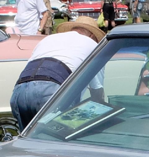 1971 Ford Ranchero - A man wearing a straw hat and back brace examines a framed picture placed on the dashboard of a 1971 Ford Ranchero.