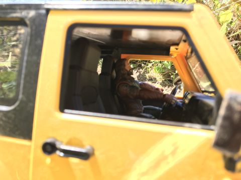 1989 Ford Bronco - Close-up view of the interior of a yellow toy SUV, a figurine seated at the steering wheel.