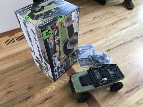 1989 Ford Bronco - A new RC rock crawler kit is unboxed, revealing the vehicle and its components laid out on a wooden floor.