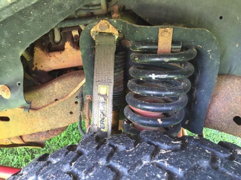 1996 Ford Bronco - Detail shot of a vehicle's suspension system, showing a coil spring and a yellow strap.