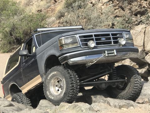 1991 Ford Bronco - This modified Ford Bronco navigates a challenging rocky trail with its suspension clearly articulated.